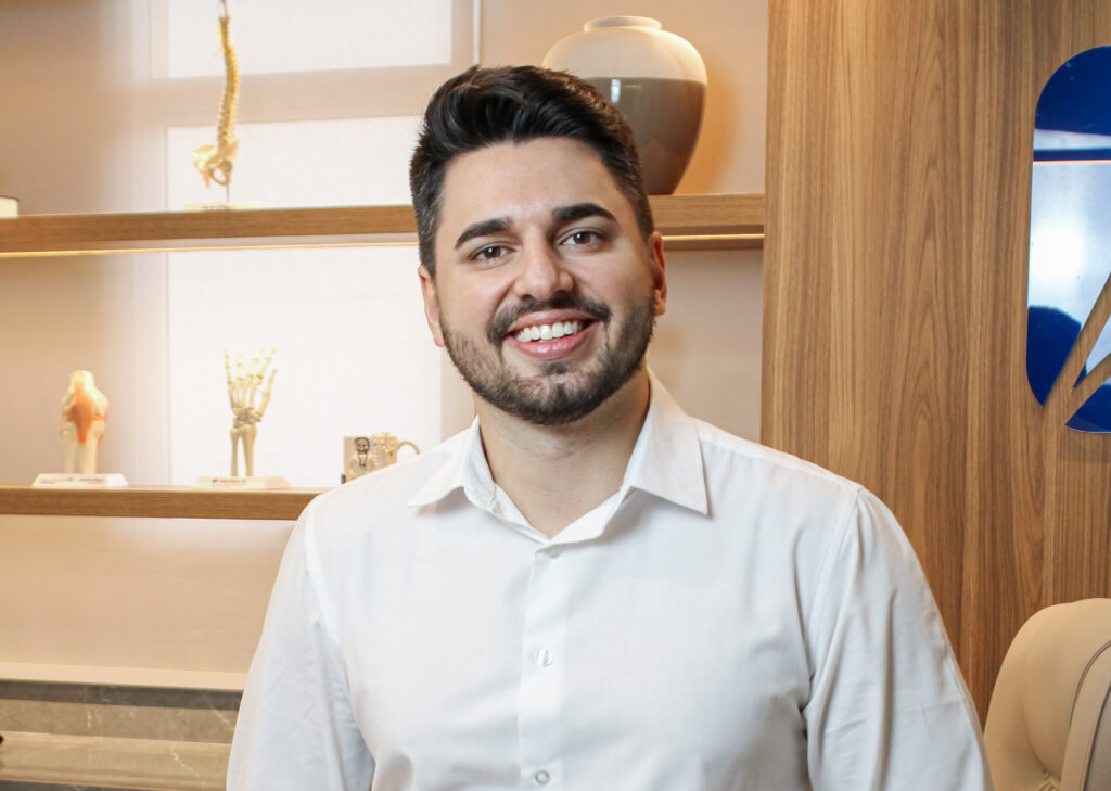Dr. Guilherme Novato sorrindo em seu consultório